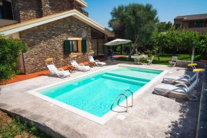 una piscina con sillas y sombrilla en Villa Patrizia con piscina privata, en Stintino