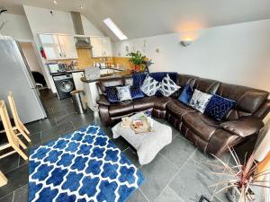 a living room with a brown leather couch and a table at The Mermaids Watch Pendine DOG FRIENDLY in Pendine