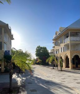 an empty street with a building and a palm tree at Duplex Côté Mer in Filaos