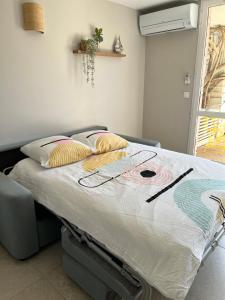 ein Bett mit einem Gemälde darauf in einem Schlafzimmer in der Unterkunft Le Lavandou "Cavalière" -Rez de jardin bord de mer , ATOM in Le Lavandou