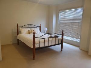 1 dormitorio con cama con marco de madera y ventana en House on the Heights, en Lyndhurst