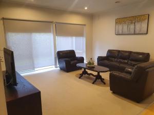 a living room with two leather furniture and a tv at House on the Heights in Lyndhurst