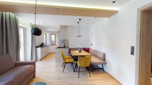 salon ze stołem i żółtymi krzesłami w obiekcie Alpen Quartier w mieście Uderns