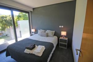 a bedroom with a bed and a large window at Apartamento Lobo - Casas Barca do Rio - Geres in Geres