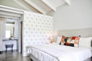 a white bedroom with a large bed and a wall at De Hoop Farm - Mountain View in Breërivier