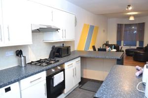 a kitchen with a stove top oven next to a living room at Cozy home near city, sleeps 5, Free Parking, WIFI in Liverpool