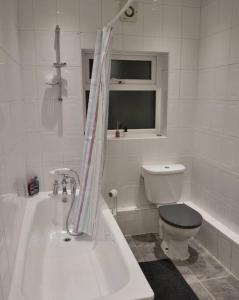 a white bathroom with a toilet and a bath tub at Cozy home near city, sleeps 5, Free Parking, WIFI in Liverpool