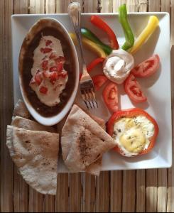 einen Teller mit Essen mit einer Schüssel Dip und Gemüse in der Unterkunft Hayaat siwa hot spring in Siwa