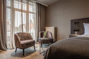 a hotel room with a bed and a chair and window at Hotel Britannia in Knokke-Heist