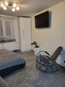 a bedroom with a chair and a television on the wall at DEIZY Apartamenty in Wągrowiec