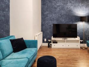 a living room with a blue couch and a tv at Riverside Cottage in Larkhall