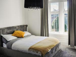1 cama con almohadas amarillas en un dormitorio con ventana en Riverside Cottage, en Larkhall
