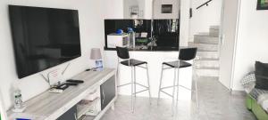 a kitchen with a bar with two stools and a tv at Castillo Mar 95 in Caleta De Fuste