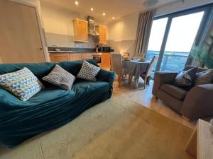 a living room with a green couch and a kitchen at Modern Spacious studio close to station in London