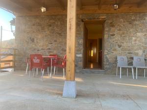 a table and chairs on a patio with a stone wall at La casa de la valla azul (San Miguel de Langre) in San Miguel de Langre