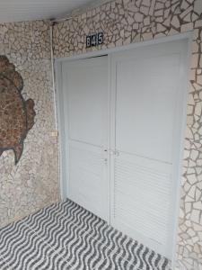 a white garage door with a sign on a stone wall at Village Galés Maragogi in Maragogi