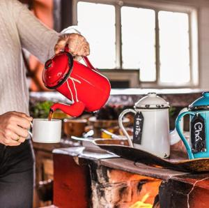 Uma mulher está a deitar café numa chávena. em Pousada Meu Recanto em Conceição da Ibitipoca