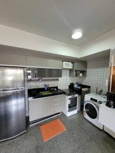 Una cocina con electrodomésticos de acero inoxidable y lavadora y secadora. en EXCELENTE Apto Edifício Santorini, en Maceió