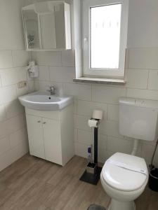 a bathroom with a toilet and a sink and a window at Pension Lavendel in Harztor