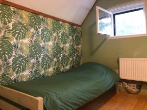 - une chambre avec un lit vert et du papier peint vert et blanc dans l'établissement Forest-side home by recreational lake, à Kunfehértó