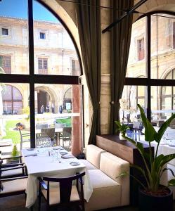 Un comedor con una mesa y un gran ventanal. en Hotel Real Colegiata San Isidoro, en León