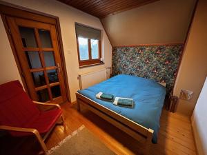 a small bedroom with a bed and a chair at Forest-side home by recreational lake in Kunfehértó