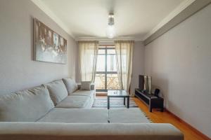 uma sala de estar com um sofá branco e uma televisão em Matosinhos Seaside Apartment by Vacationy em Matosinhos