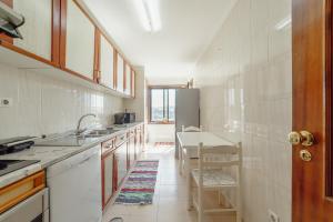 uma cozinha branca com um lavatório e uma mesa em Matosinhos Seaside Apartment by Vacationy em Matosinhos