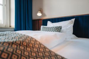 Schlafzimmer mit einem Bett mit weißer Bettwäsche und Kissen in der Unterkunft Hotel Amalia - Boutique Hotel in Landshut