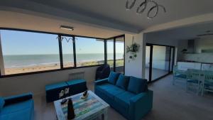 una sala de estar con muebles azules y vistas a la playa. en Monte Hermoso Premium en Monte Hermoso