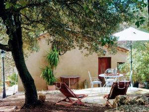 a patio with chairs and a table and an umbrella at Villa San Marco chambre d hôtes in Lorgues