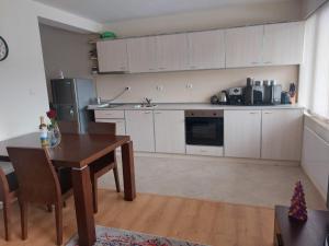 uma cozinha com armários brancos e uma mesa de madeira e uma mesa e cadeiras em Apartment Pirin em Bansko