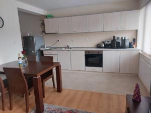 a kitchen with white cabinets and a wooden table and a table and chairs at Apartment Pirin in Bansko