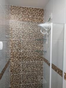 uma casa de banho com um chuveiro e uma porta de vidro em Flat JOÃO PESSOA JACUMÃ em Jacumã