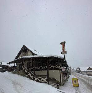 un edificio cubierto de nieve con un cartel delante en Palaga Bukovel, en Bukovel