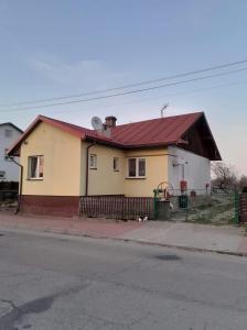 una casa amarilla con techo rojo en una calle en Jak w Domu en Lubaczów
