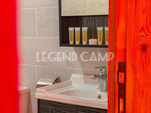 a bathroom with a sink and a sign on the wall at Rum Hatem Camp in Wadi Rum