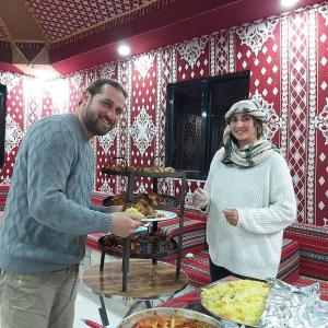 um homem e uma mulher ao lado de uma mesa com pizza em Rum Hatem Camp em Wadi Rum
