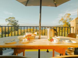 a wooden table with an umbrella on a balcony at Residence Maïna in Cargèse