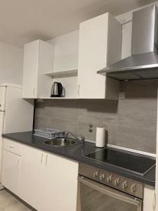 uma cozinha com armários brancos e um lavatório em Blue Sky Apartment em Zagreb