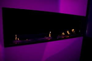 a black fireplace with flames in a purple room at Suite Luxury BDSM in Rome