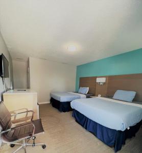 ein Hotelzimmer mit 2 Betten und einem Stuhl in der Unterkunft Sand Dollar Motel in Atlantic Beach