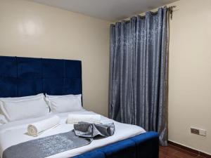 a bed with a blue headboard in a room at Bliss haven gardens two bedroom apartment in Nairobi