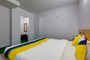 a bedroom with a large white bed with colorful pillows at Itsy By Treebo - Shri Gv Inn 600 Mtrs From Tiffin Top in Nainital