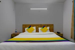 a bedroom with a large white bed with colorful pillows at Itsy By Treebo - Shri Gv Inn 600 Mtrs From Tiffin Top in Nainital