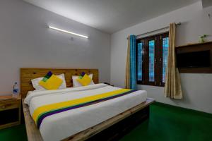 a bedroom with a large bed with a colorful blanket at Itsy By Treebo - Shri Gv Inn 600 Mtrs From Tiffin Top in Nainital