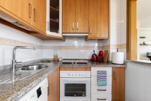 Una cocina con gabinetes de madera y un fregadero. en CB Living- Spacious sea view duplex with private jacuzzi, en Orihuela Costa