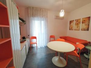 sala de estar con mesa blanca y sillas naranjas en Tre Continenti - Appartamento con parcheggio privato, en Ronchi dei Legionari