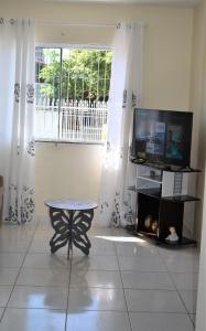 um quarto com uma mesa, uma televisão e uma janela em Casa Aconchegante em Itapema em Itapema