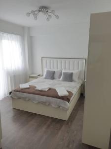 a white bedroom with a large bed with pillows at Leaf House in Sibiu
